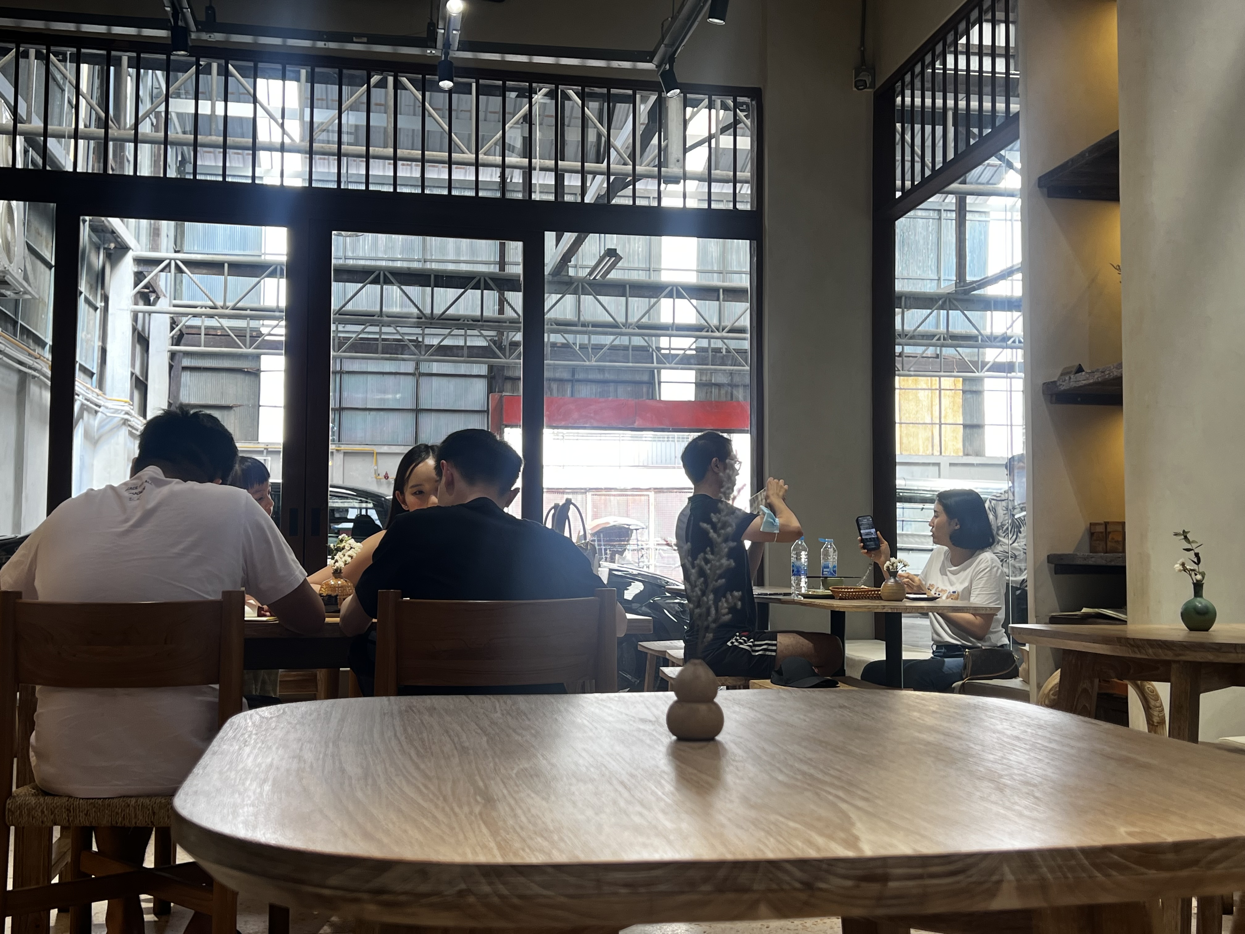 大きな窓と木のテーブルがあるSàat Bangkokの客席