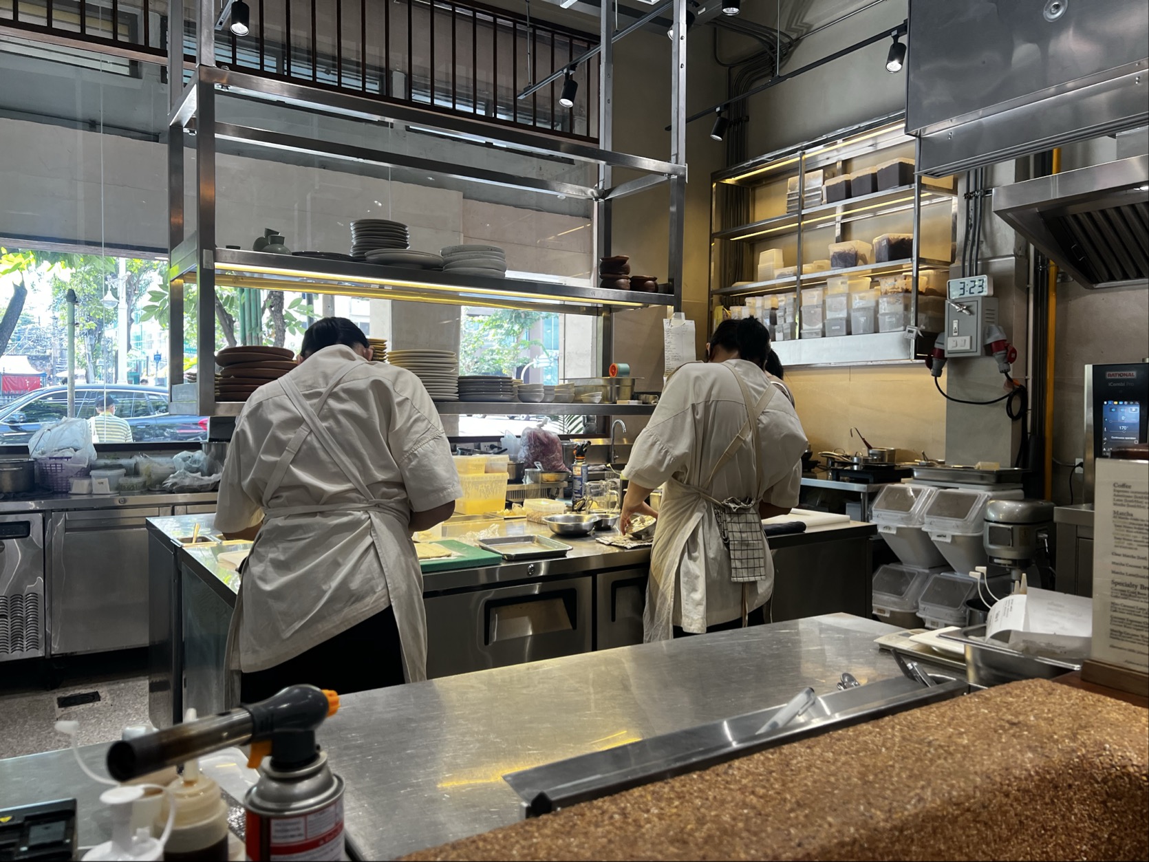 Sàat Bangkokのオープンキッチンで料理を仕上げるスタッフ